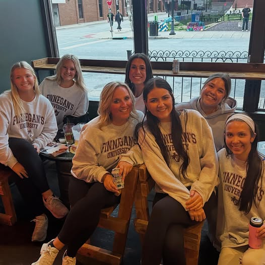Group of friends in Finnegan's University sweatshirts gathered at the pub