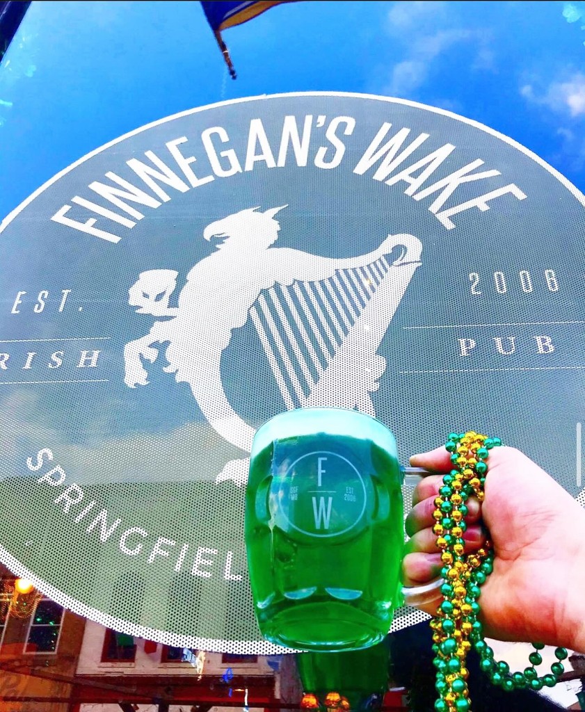 Green beer held up in front of the Finnegan's Wake logo